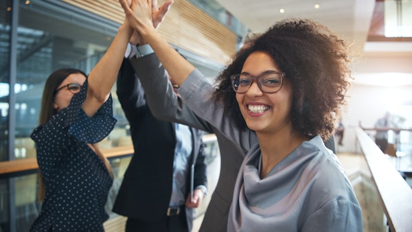 A group of at least three adults giving a collective high-five gesture. A Black female participant is smiling and facing the camera.